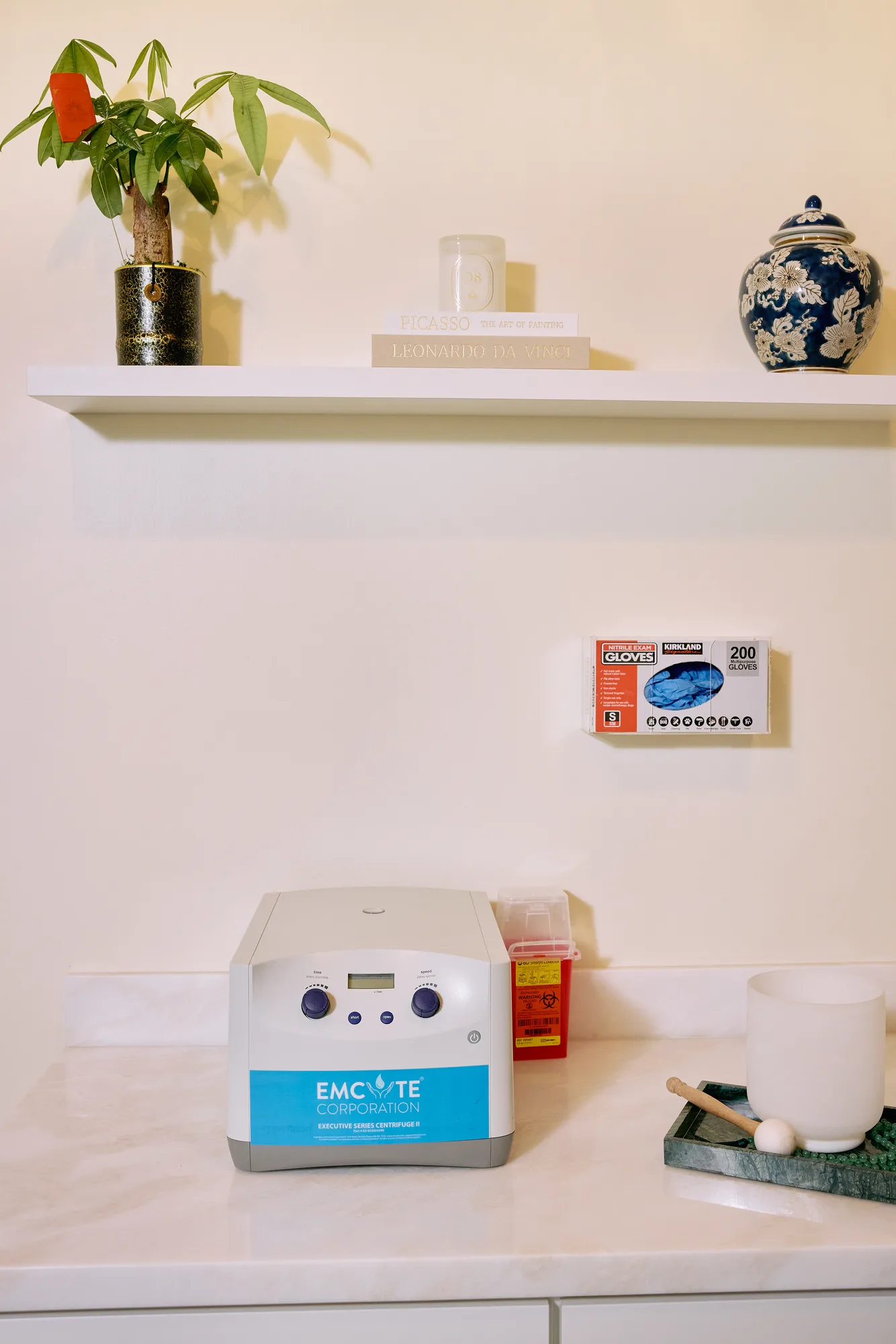 Blood-preparation equipment on the clinic counter beneath a shelf of books and ceramics